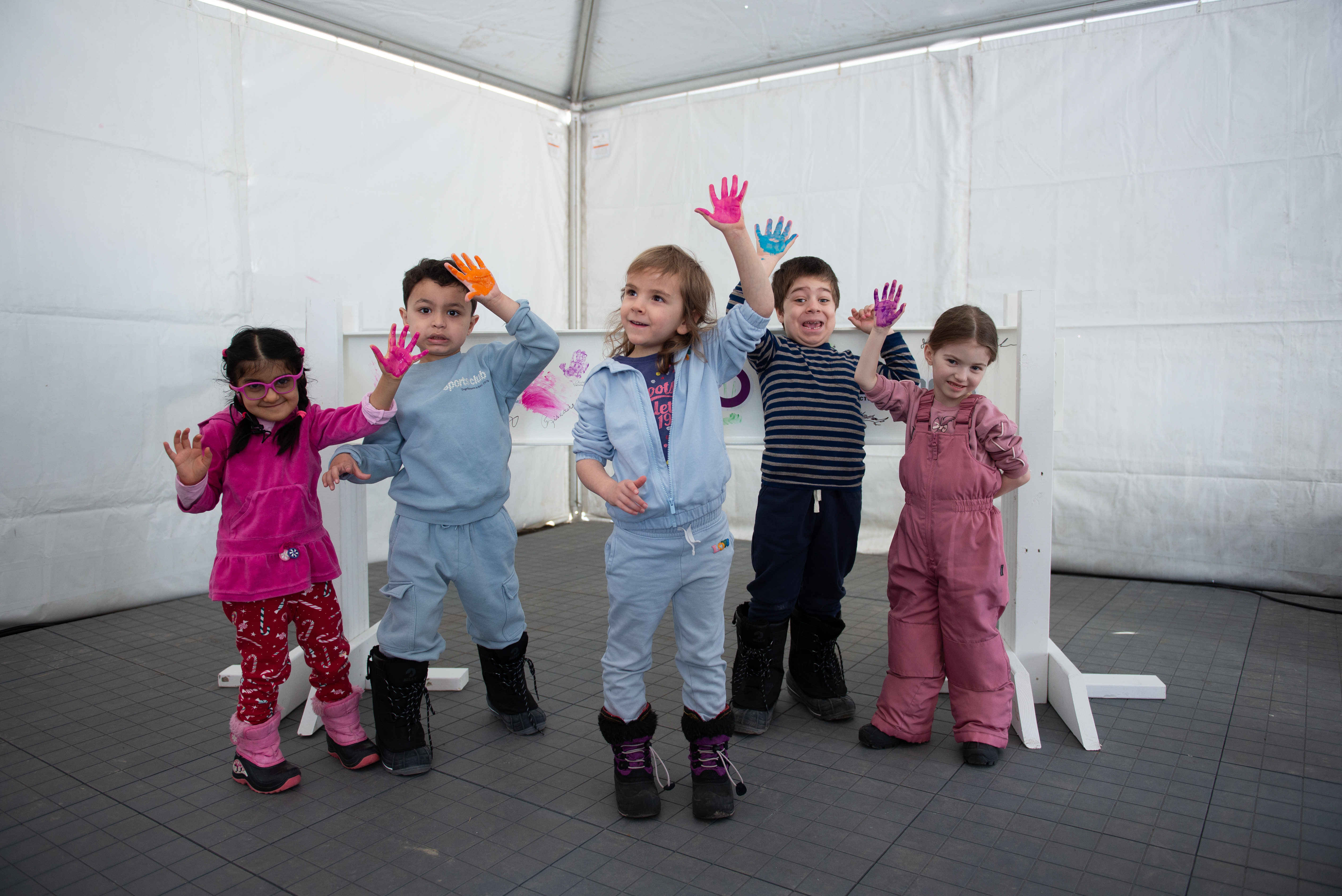 Kids with painted hands in front of white metal construction beam